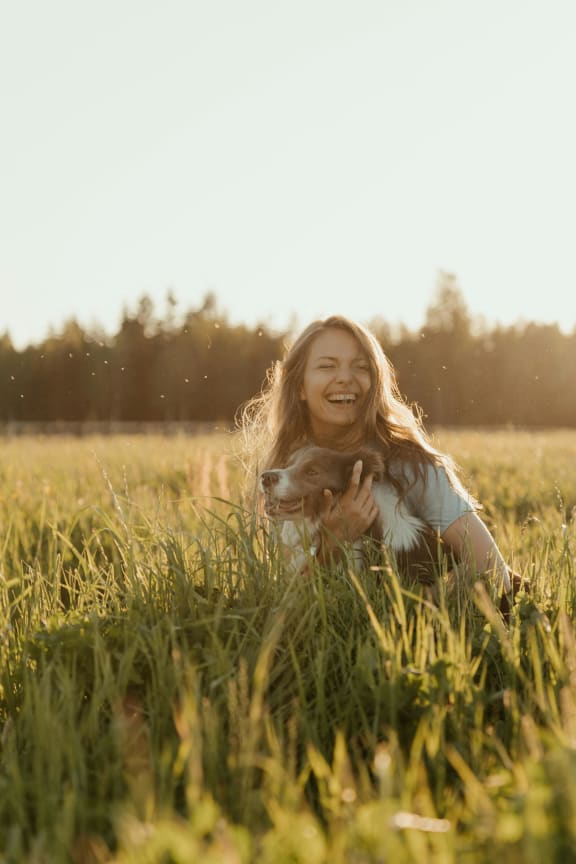 a young woman laying in the grass with her dog