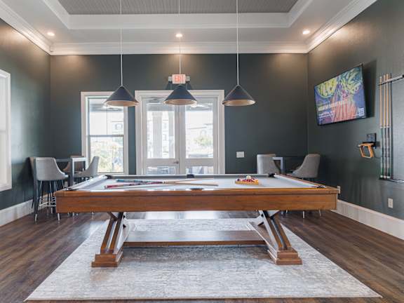 A room with a pool table and a television mounted on the wall.