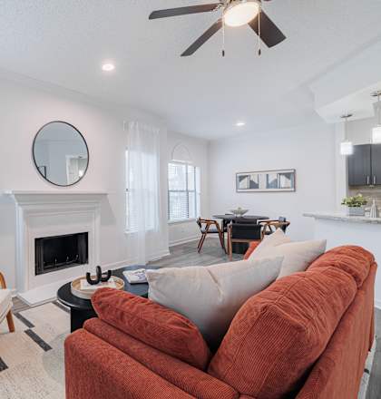 A living room with a fireplace, a sofa, a chair, and a potted plant.