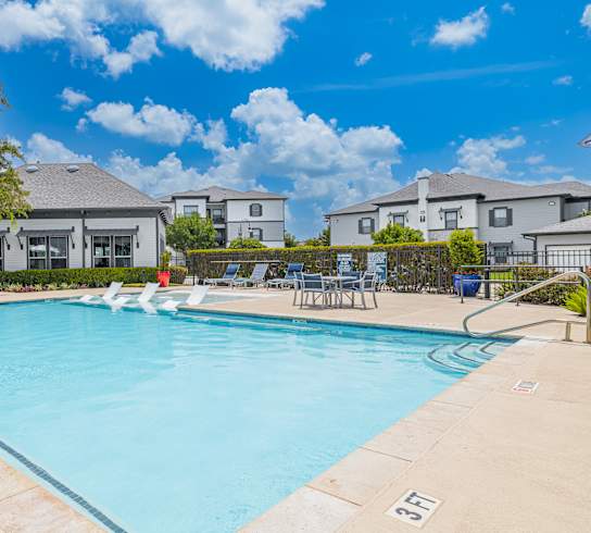 A swimming pool surrounded by lounge chairs and a clear blue sky.