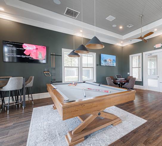 A room with a pool table and a TV mounted on the wall.