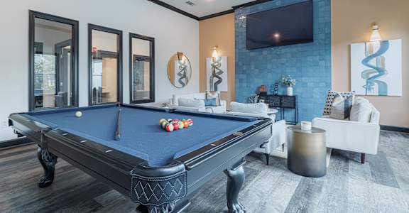 A pool table is in the middle of a room with a television and a couch.