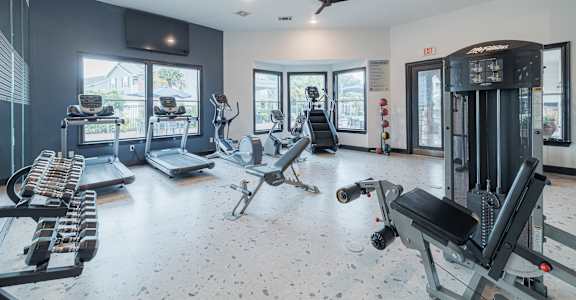 A spacious gym with a variety of equipment including treadmills, elliptical machines, and weight machines.