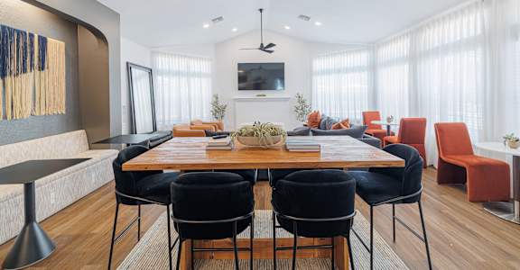 A modern dining room with a wooden table and black chairs.