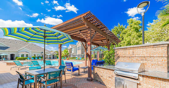 A patio with a table and chairs under a striped umbrella.