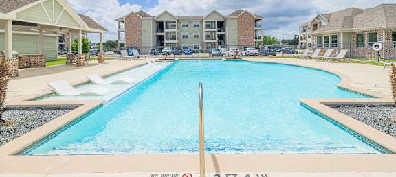 A swimming pool in front of apartment buildings with a sign that says "NO DIVING 3 FT 4 IN".