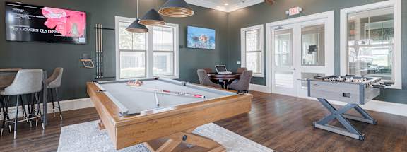A room with a pool table and a TV mounted on the wall.