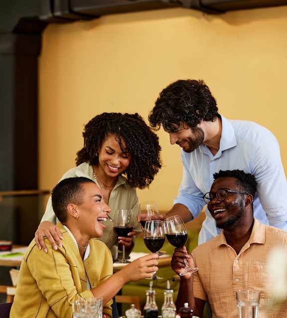 Four people are sitting around a table with food and drinks.