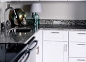 Thumbnail 3 of 4 - A kitchen with white cabinets and a black stove top at Hampton Plaza Apartments, Towson, MD, 21286