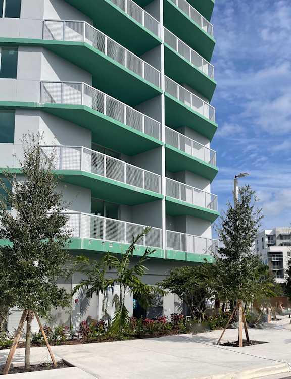 a building on the corner of a street with cars parked in front of it at Meridian Point at Goulds Station in Miami, FL, 33170
