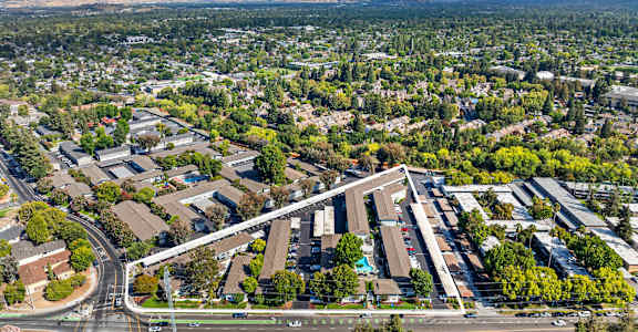 A large building complex is surrounded by a green landscape.