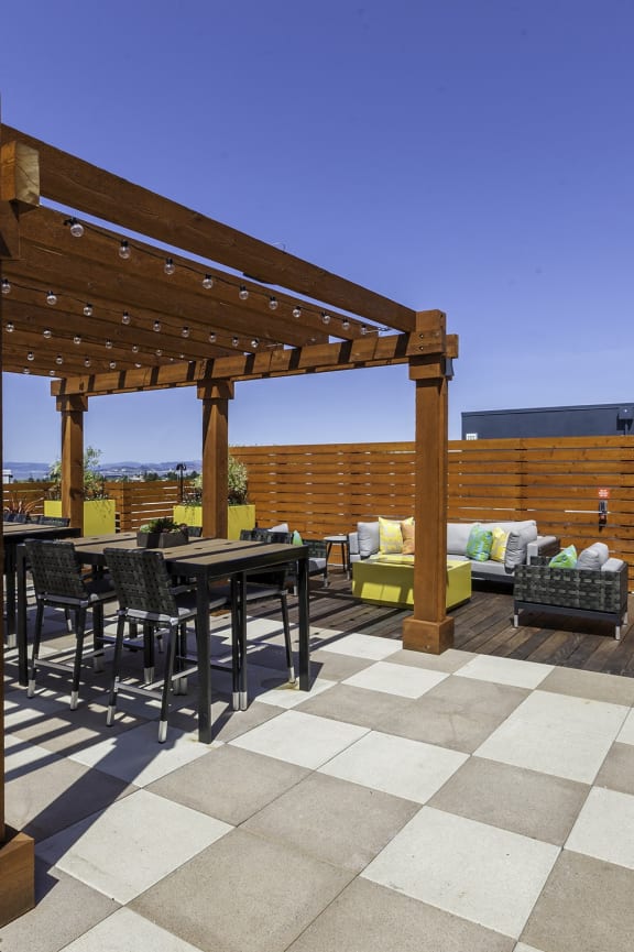a rooftop patio with tables and chairs and a wooden pergola