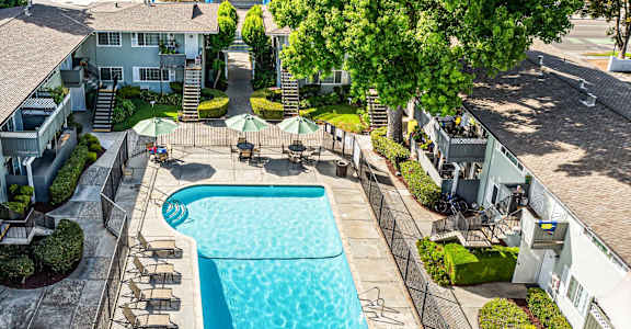 A swimming pool surrounded by a concrete patio and a grassy area.