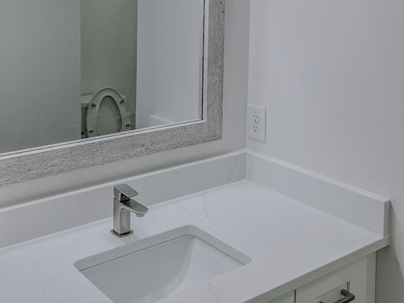 A bathroom with a white sink and a mirror above it.