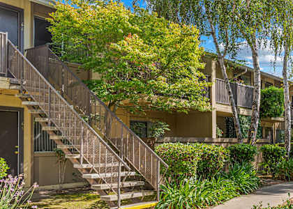 A building with a staircase and trees in front.