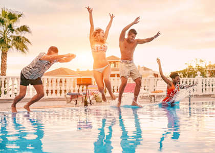 Four people jumping into a pool.
