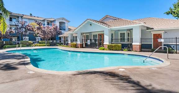 A swimming pool in front of a house with a fence around it.