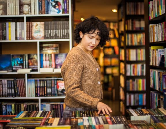 a woman looking at books in a bookstore