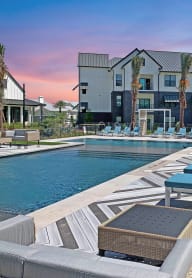 an outdoor pool with lounge chairs at the resort on a sunny day