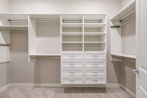 a walk in closet with white shelves and drawers at Expo, Minnesota