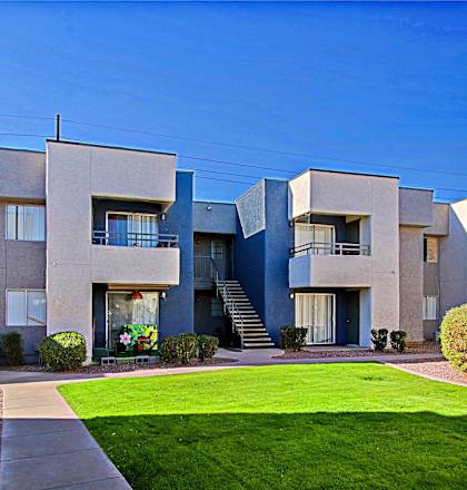 a row of apartments with balconies and green grass