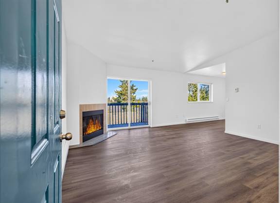 A room with a fireplace and a view of trees outside the window.