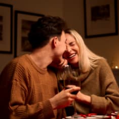 a man and woman sitting at a table with a glass of wine