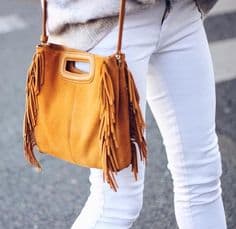 a woman in white jeans and an orange purse