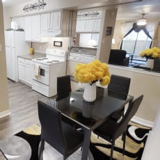 a kitchen with white appliances and a black dining table with yellow flowers