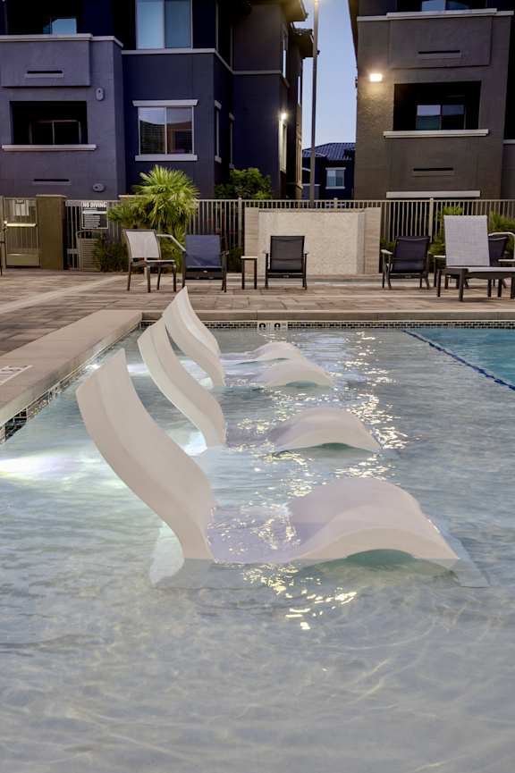 Shallow water sundeck with tanning chairs in water at Level 25 at The Curve by Picerne, Las Vegas, Nevada