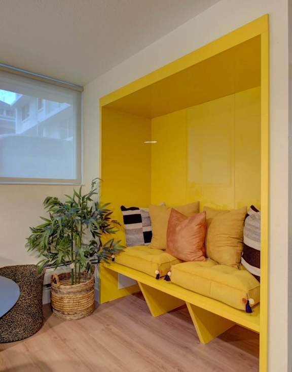 A yellow sofa with a plant on a table in a room.
