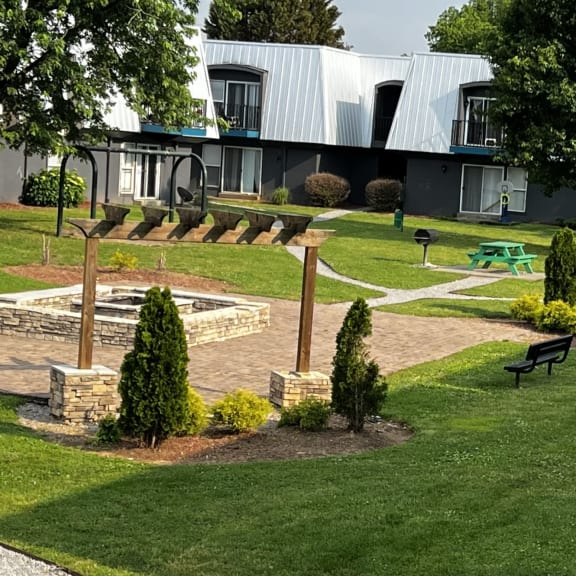 a grassy area with a fountain and benches in front of a building
