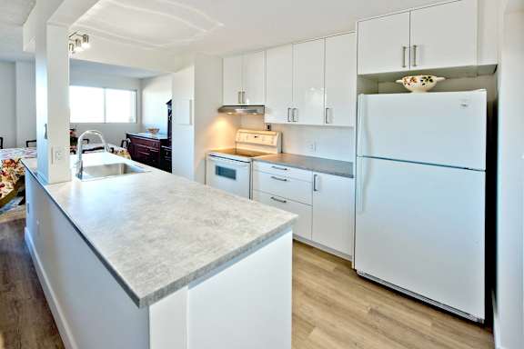 A kitchen with white cabinets and a marble countertop.