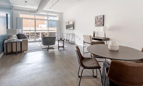A modern living room with a grey table and brown chairs.