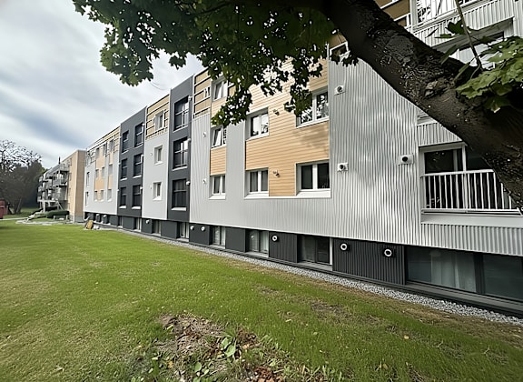 A large brick apartment building with a green lawn in front.