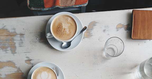 two people sitting at a table with coffee and a piece of cake