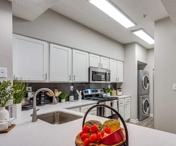 a kitchen with white cabinets and a counter top with a fruit basket