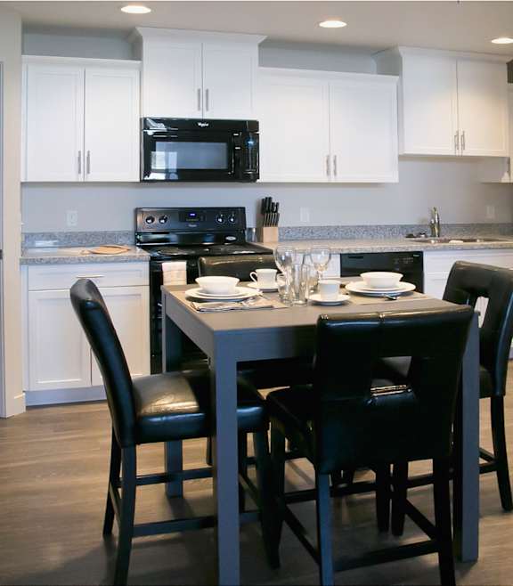 a kitchen with white cabinets and a table with black chairs