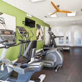 a gym with various exercise equipment and green walls