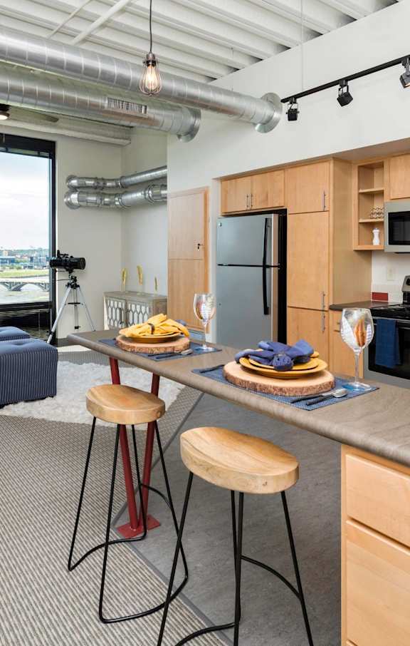 an open kitchen and living room with a large counter top at City Square Lofts, Des Moines, IA