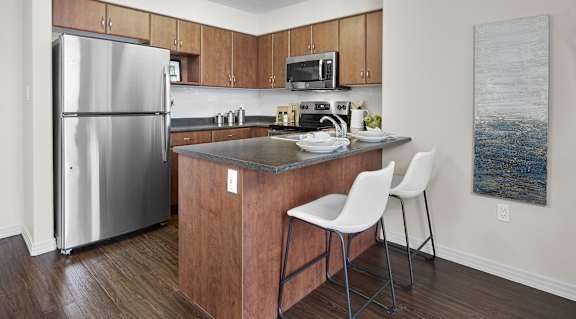 A kitchen with a refrigerator, microwave, and stove top oven.