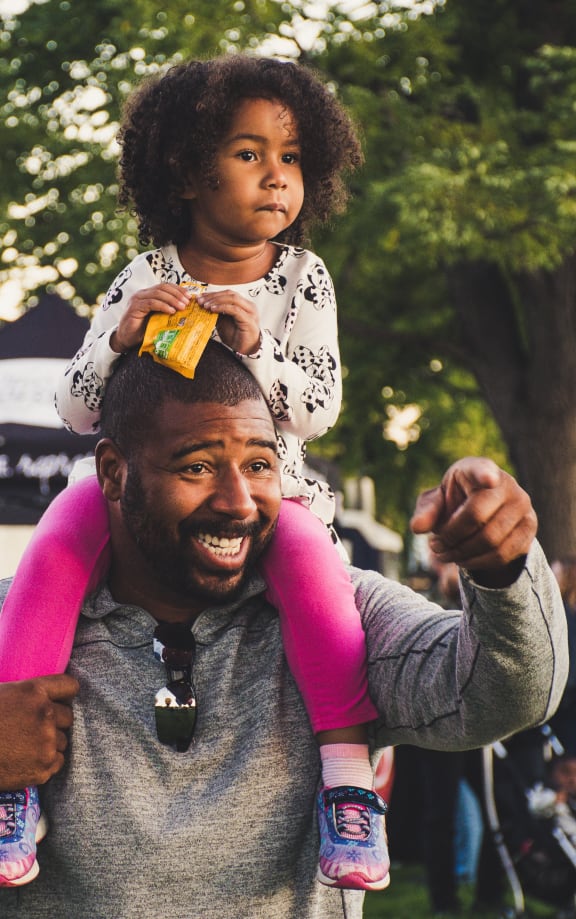 a man holding a little girl on his shoulders