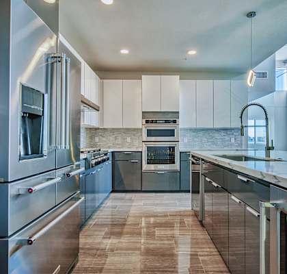 A modern kitchen with stainless steel appliances and wooden flooring.