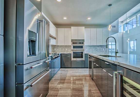 A modern kitchen with stainless steel appliances and wooden flooring.