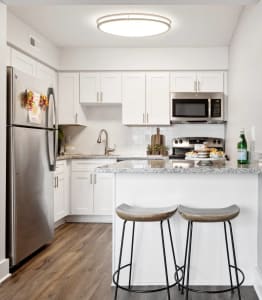 a kitchen with white cabinets and a counter with two stools