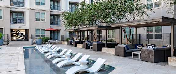 A pool surrounded by white chairs and a building in the background.