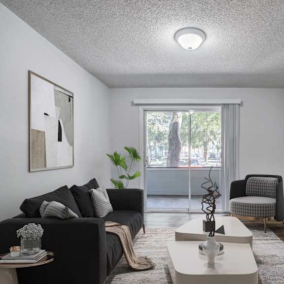 A living room with a grey couch, a white coffee table, and a flat screen TV mounted on the wall.