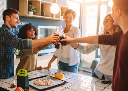 A group of people toasting with drinks in a kitchen.