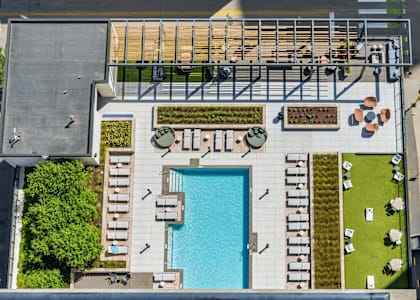 An aerial view of a pool surrounded by lounge chairs and greenery.