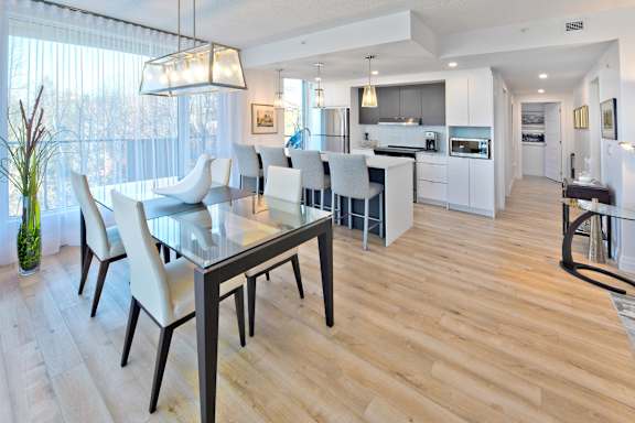 A modern kitchen with a glass dining table and chairs.